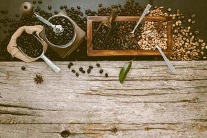 Various of roasted coffee beans in wooden box with manual coffee grinder setup on shabby wooden background.