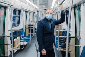 Coronavirus crisis in 2020. Man commutes to work in empty underground, uses public transport, uses protective face mask against virus, wears protective surgical mask during quarantine period photo