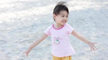 retrato de feliz y encantadora niña asiática de 4 años, pequeña niña preescolar sonriendo y extendiendo las manos, diviértete. concepto de libertad. foto