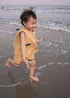 Linda niña asiática de 3 años disfrutando de las vacaciones en el mar, en verano. foto