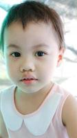 Headshot of charming 3 years old cute baby Asian girl, little toddler child with adorable brown less hair. photo