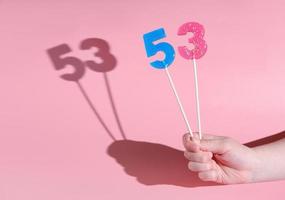 girl's hand holding a number 5 and 3 shaped lolipop. photo