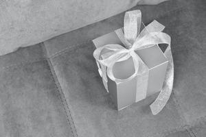 Último color gris del año 2021. caja de regalo en un sofá gris. foto