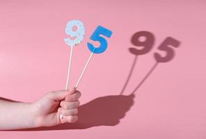 girl's hand holding a number 95 shaped lolipop. photo