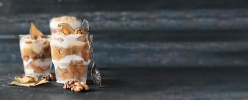 Pear trifle, chocolate biscuit, layered dessert with caramel, pear and gentle cream cheese on grey background. Selective focus photo