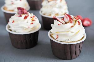 low carb keto cupcakes with frosting. ketogenic diet sweets. muffins with almond flour and sweetener. cream cheese filling and dry strawberries and pistachios photo