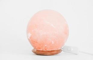 round himalayan Pink salt lamp on white background. wellness and clean air in the room. healthy sleep help. photo