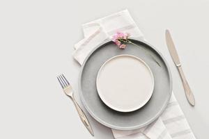 empty grey plates on a table with fork and knife. spring menu concept. trendy nordic minimal style tableware. restaurant menu mock up. top view, copy space. scandinavian tableware design photo