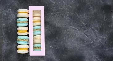macarrones en colores azul pastel y beige sobre fondo gris. una caja de galletas. postre dulce francés hecho de harina de almendras. macaron casero. copie el espacio foto
