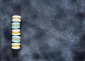 macarrones en colores azul pastel y beige sobre fondo gris. postre dulce francés hecho de harina de almendras. macaron casero. copie el espacio foto