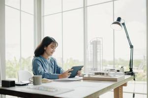 Selective focus, Asian female architect or engineer Drawing the design of the building's interior using a tablet. Asian female architect or engineer Sit and analyze, design projects in the office. photo