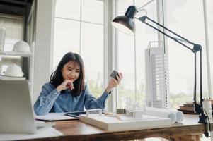 Selective focus, Asian female architect or engineer Currently considering materials for designing modern condominiums. Asian female architect or engineer Sit and analyze, design projects in the office photo