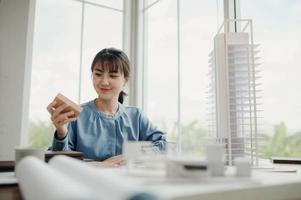 Selective focus, Asian female architect or engineer Currently considering materials for designing modern condominiums. Asian female architect or engineer Sit and analyze, design projects in the office photo