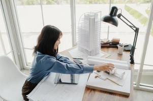 enfoque selectivo, arquitecta o ingeniera asiática que actualmente considera materiales para diseñar condominios modernos. arquitecta o ingeniera asiática sentada y analizando, diseñando proyectos en la oficina foto