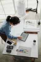 Selective focus, Asian female architect or engineer Drawing the design of the building's interior using a tablet. Asian female architect or engineer Sit and analyze, design projects in the office. photo