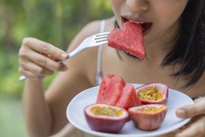 Close up of woman raised a plate of eat fruit with watermelon and passion fruit. Girl enjoy fruit for lunch, wellbeing diet concept. Concept of health photo