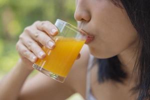 Close up of woman drink orange juice. Girl enjoy fruit juice for lunch, wellbeing diet concept. Concept of health photo