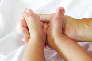 Tiny baby feet or new born baby feet placed on the palm of mother and background is white diapers. photo