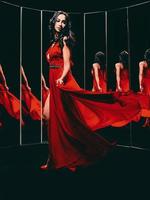 Portrait of beautiful brunette woman in red shoes and dress turning around and dancing near the mirrors photo