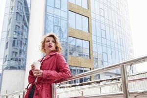 bonito pelo rubio. mujer bonita adulta con un cálido abrigo rojo camina por la ciudad los fines de semana foto