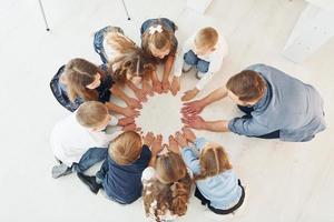 Top view. Man with his kids students in holding hands for success. Conception of education photo