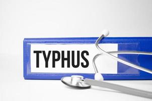 typhus word on file folder and stethoscope on white background photo