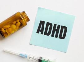 pastillas, un bolígrafo y un cuaderno con la inscripción adhd. concepto medico foto