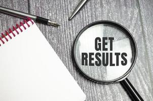 get results symbol on magnifier and pen on wooden background photo