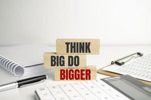 Think Big, Do Bigger Motivation quote . text on wooden cubes photo