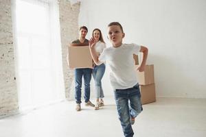 avanzando rápido. estado de ánimo juguetón del niño. la familia tiene mudanza a una nueva casa. desempacar cajas de mudanza foto