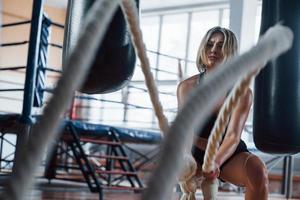 haciendo su mejor esfuerzo. mujer rubia deporte hacer ejercicio con cuerdas en el gimnasio. mujer fuerte foto