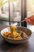 selective focus, Tagliatelle with pork stew and vegetables in a bowl served on wooden table, Spaghetti Pasta with meat. photo