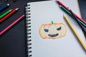 cuaderno en el escritorio, dibujando calabaza en el cuaderno foto