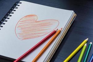 cuaderno en el escritorio, dibujo de corazón en el cuaderno foto