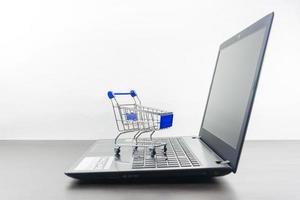 Computer notebook blank screen with shopping cart on wood table photo