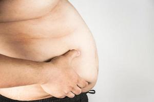 cuerpo de hombre con sobrepeso con las manos tocando la grasa del vientre foto