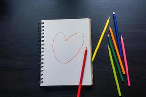 cuaderno en el escritorio, dibujo de corazón en el cuaderno foto
