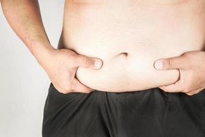 cuerpo de hombre con sobrepeso con las manos tocando la grasa del vientre foto