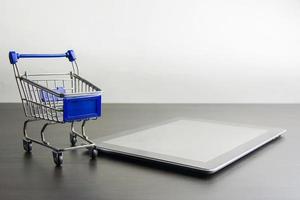 tableta con carrito de compras en madera, significa comprar en línea