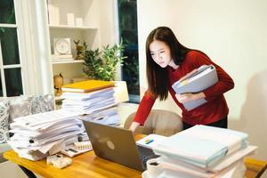 Urgent job. Asain woman doing overtime at home at night. Workaholic people concept photo