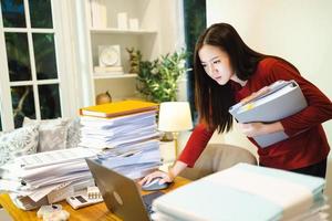 Urgent job. Asain woman stand at desk at home at night. Workaholic people concept photo