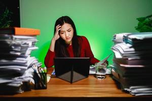 A stressed female freelancer makes her report on a digital tablet. Workaholic people concept photo