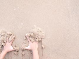 The kids' hands push the wet sand on the beach photo