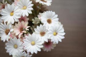 white and pink flowers on the wooden table with yellow pollen photo