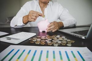 woman hand putting money into piggy photo