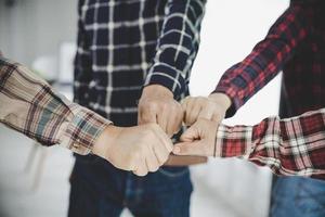 jóvenes empresarios poniendo sus manos juntas foto