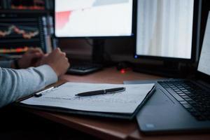 Close up view. Man working online in the office with multiple computer screens in index charts photo