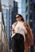 Warm coat that taken off is in hand. Young beautiful girl in warm clothes have walk in the city at her weekends time photo