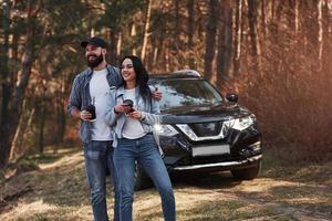 tiempo de fines de semana. disfrutando de la naturaleza. una pareja ha llegado al bosque en su nuevo auto negro foto