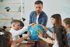 Touching the Earth globe. Group of children students in class at school with teacher photo